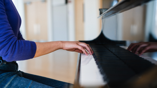Person playing a piano with focus on hands