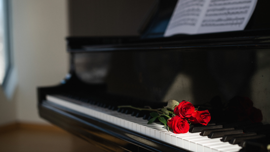 Red roses on a piano keyboard with sheet music in the background
