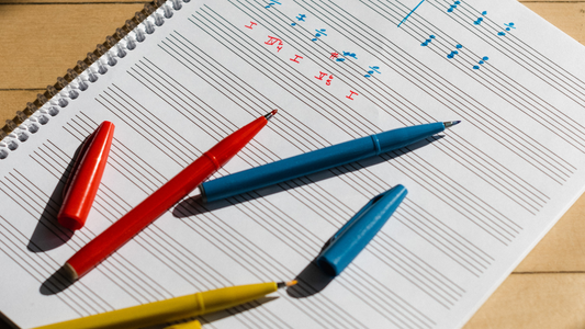 Colorful markers on a sheet of music notation paper