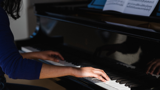 Person playing a piano with sheet music in the background