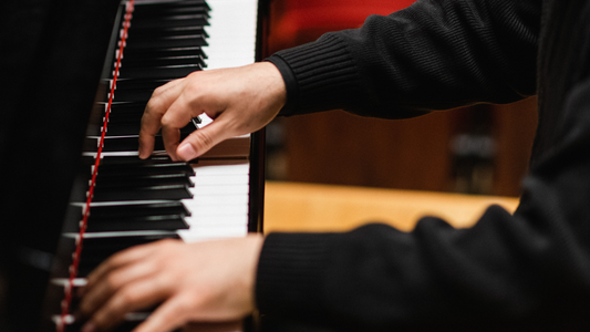 Close-up of hands playing a piano with a blurred background