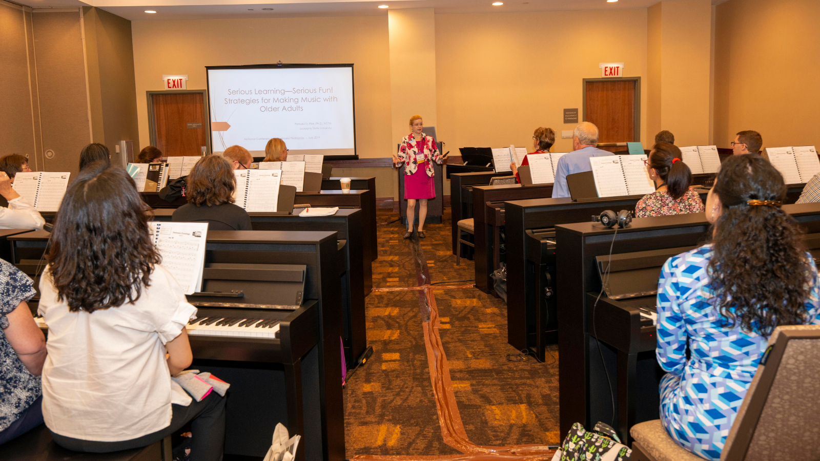Music classroom with students playing pianos and a teacher at the front.