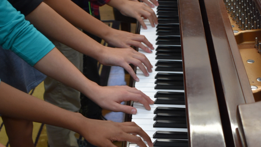Hands playing a piano with a focus on the keys
