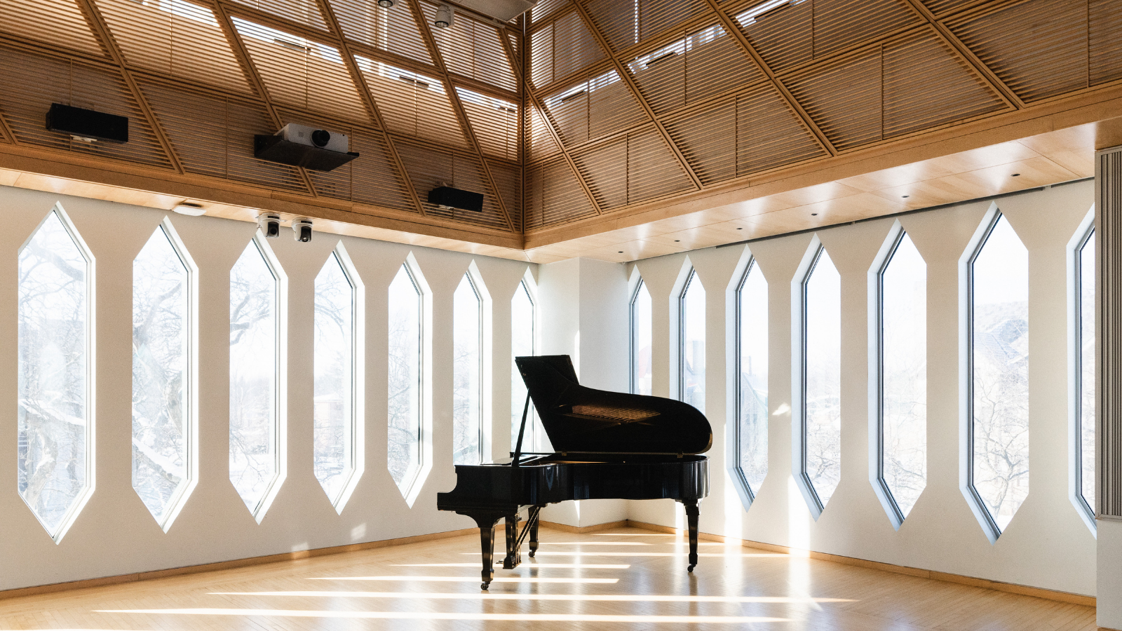 Grand piano in a room with large windows and wooden ceiling